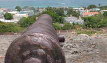 Title: Vieques and its Goliath Isabella II, Vieques, Puerto Rico, June 2012. Caption: From the years 1941 through 2003 the U.S. Navy was the prominent force that shaped the political and socio-economic climate of Vieques. Even today, despite the fact that the navy is no longer actively using the island for testing toxic and deadly weapons, its presence still looms over the lives of its inhabitants in the form of soaring cancer rates and rampant poverty. In addition, Viequenses face a growing challenge, tourism. With the small city enveloped between the canons of the past and an increase of cruise ships, this photo encompasses the past, present, and future of this exploited municipality of the U.S. territory of Puerto Rico.