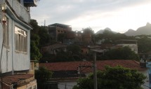 Title: Sunrise Caption: This photo was taken in a neighborhood called Tijuca which is located in Rio de Janeiro, Brazil. I traveled to Brazil as part of my field work for my masters thesis. The Brazilians that live here are very proud of their home. These homes represent a simple brick and mortar vernacular yet are sturdy and maintain the rich culture of the inhabitants. The dwellings are multi-level and house several generations of families. The landscape of the hills boasts a luscious green oasis of towering hills and glorious rooftop views. The trees shown offer shade to the homes and also bear fruit to several local and exotic fares. The sunrise illuminates the simplistic beauty of the area.