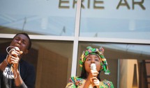 Title: World Refugee Day at the Erie Art Museum. June 27, 2012 Caption: World Refugee Day at the Erie Art Museum brought together the growing refugee community in Erie, Pennsylvania. A city of some 101,786 residents as of 2010, an estimated 30,000 are of refugee status. Majority of the refugee population hail from Southern Sudan, the Congo, Bhutan, Syria, Ukraine, and Burma. Pictured is Oliver Okende and his sister Grace. As teenage refugees from the Congo, the struggles of their travels to Erie from refugee camps are encapsulated in Swahili praise and worship songs. Their voices in a cappella rang through the square and brought light to many of the refugee faces in the crowd.