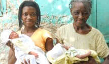 Category: PEOPLE

Title: Birthing Haiti

By: Bonnie Ruder

Jacmel, Haiti. June 2010.
Caption: A seventy-year-old matwon (traditional midwife) holds a baby outside her birth clinic in the mountains surrounding Jacmel, Haiti. She is accompanied by her apprentice and granddaughter, who is also holding a baby delivered at their birth center.