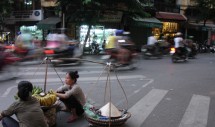 Title: Hanoi Hustle Caption: Traffic swirls around a street vendor in Hanois Hoan Kiem district.