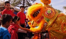 Title: Feeding the Lion, Little Saigon Tet Festival, San Diego, California, 2/5/2011 Caption: A little girl feeds money to a lion during a traditional Lion Dance at the Little Saigon Tet (New Year) Festival in San Diego, California. Students from the local martial arts school dress up as the lion and grab various fruits and vegetables from around the venue. Red envelopes containing money are typically attached to the fruits and vegetables and the money is considered payment for an enjoyable performance as well as a donation to the martial arts school. In this photograph, a little girl is directly feeding a red envelope of money to the lion in the hopes of bringing good luck and fortune to her family and community.