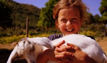 Title: Holding My Goat, San Diego County, California, 5/10/11 Caption: A boy holds a goat that he helped organically raise on a farm in northern San Diego County. The farm on which this boy lives is one of a growing number of farms in the region providing organic fruits, nuts, vegetables, eggs, milk, and cheese. The farm is operated completely by volunteers and is affiliated with The Twelve Tribes, a Christian religion outside the mainstream probably best known for running Yellow Delis in various locations around the world. Organic farms are a major component of sustainable community and carbon emission reduction strategies for local and regional governments throughout California.  