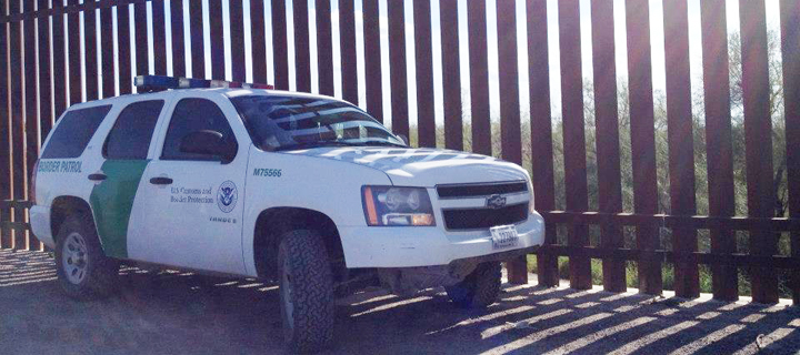 Featured Image Border agent and wall. Photo courtesy Maia Wikler