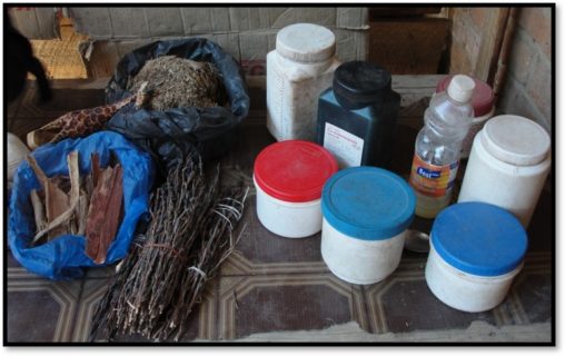 On the right are plastic jars with brightly colored caps. On the left sit a variety of herbs that resemble twigs that are tied together with string at both ends.