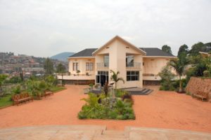 The Kigali Genocide Memorial, a building painted in cream color, surrounded by gardens providing a place for quiet contemplation about the history of the Genocide against the Tutsi.