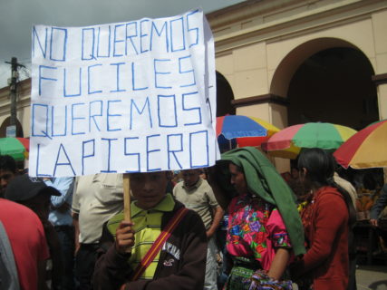 A young boy holds a sign that reads, "No queremos fuciles queremost lapisero."