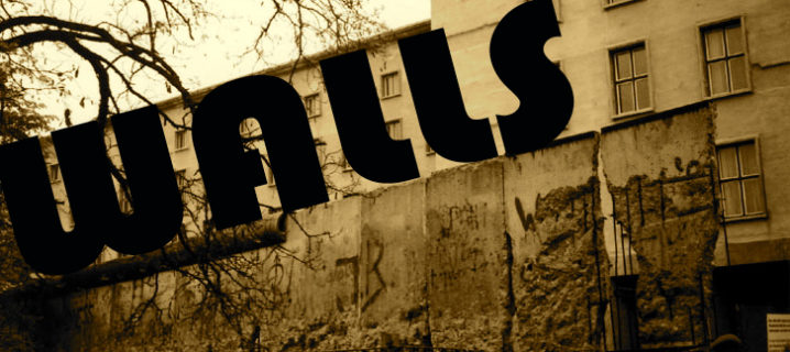 An old photo of a section of the Berlin wall that is weathered and cracked, with what looks like an apartment building behind it. The word "Walls" is written across the top of the photo.