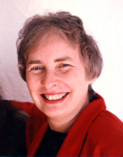 Woman with short, salt and pepper hair, smiling.