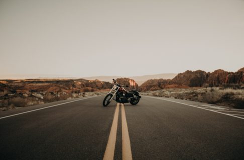 A motorcycle is parked in the middle of an empty desert road