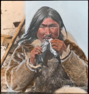 A man holds two birds to his mouth, taking a bit from each simultaneously.