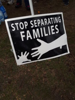 A sign from a rally to end family separation and child detention. The sign reads 'Stop separating families' and shows one hand outstretched to another.
