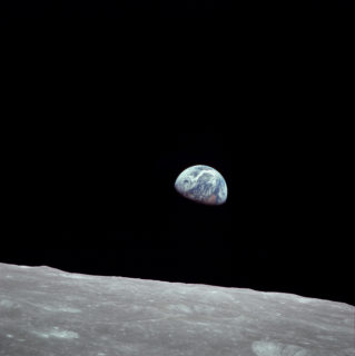 Photo of the earth from the surface of the moon. The earth looks half-full.