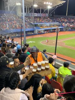 With ball play in the background a male beer vendor sells to fans.