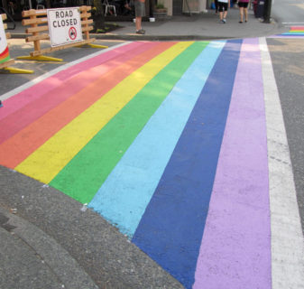 A photo of a crosswalk painted in colors of the rainbow.