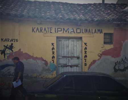 An old adobe and stucco building with a damaged tile roof that was the location of a karate studio.