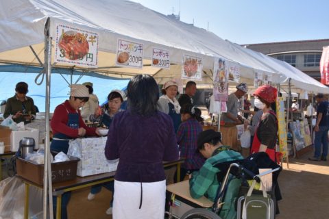 A photo of people gathering at food stands where Korean women sell Korean food at an intercultural event.
