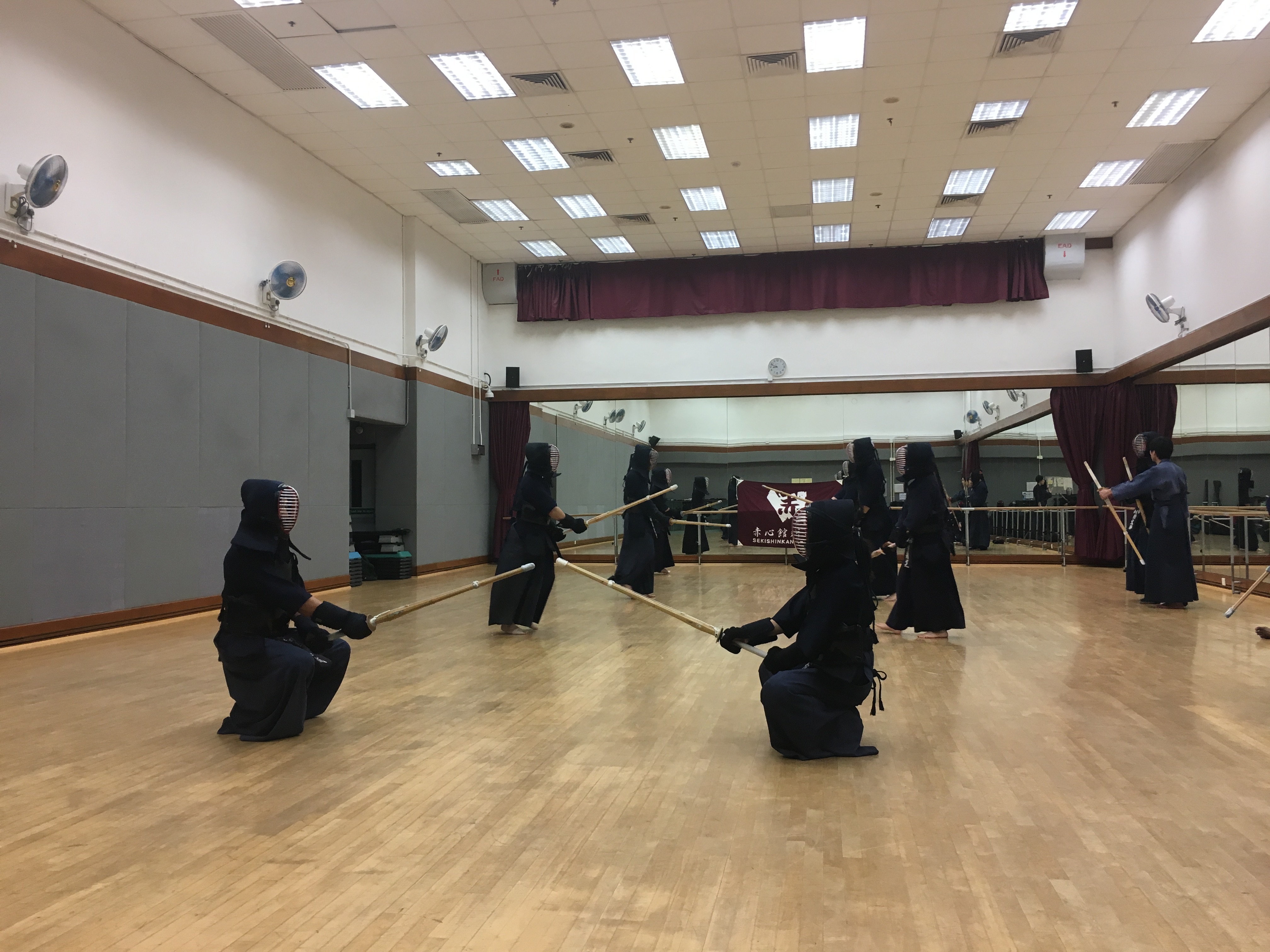 Photo of a practice room with numerous people in kendo gear.