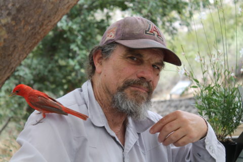 Photograph of a man with a bird on his shoulder.