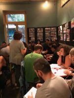 Photograph of a room filled with people sitting at tables.