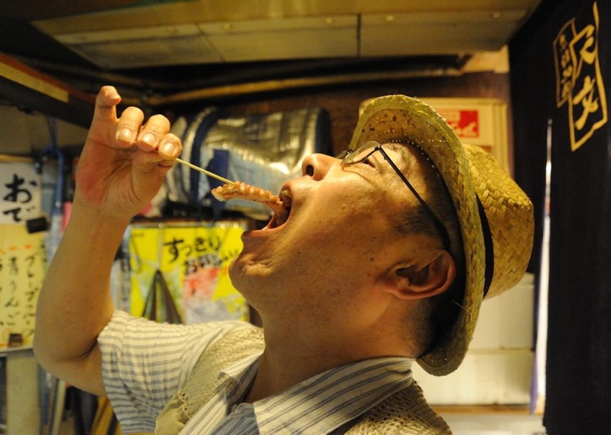 Photograph of a man eating grilled octopus