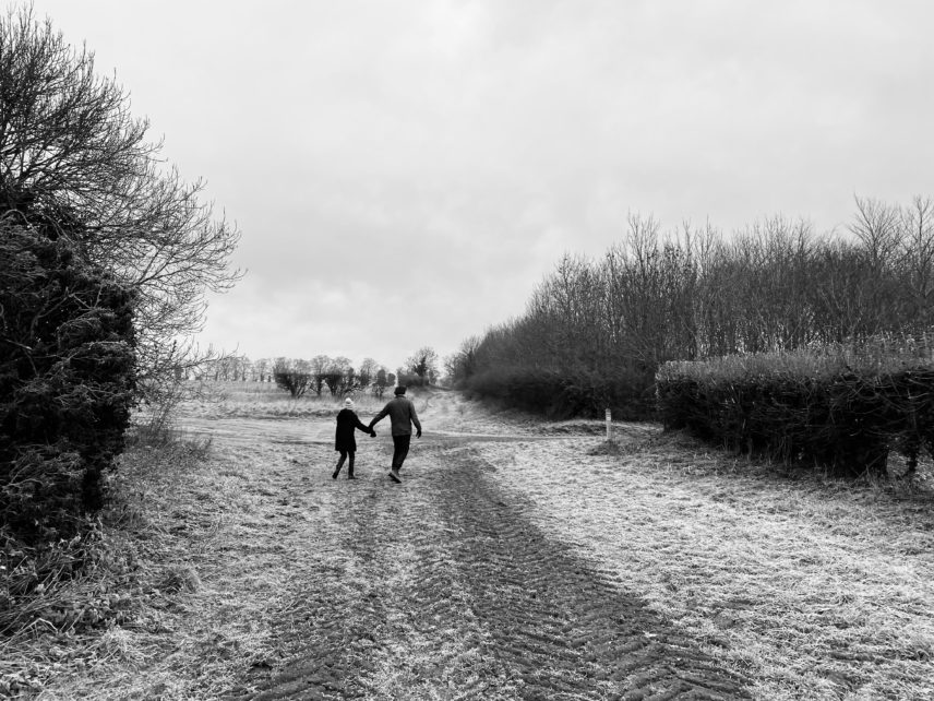 Black and white photograph of two people walking on a trail outdoors