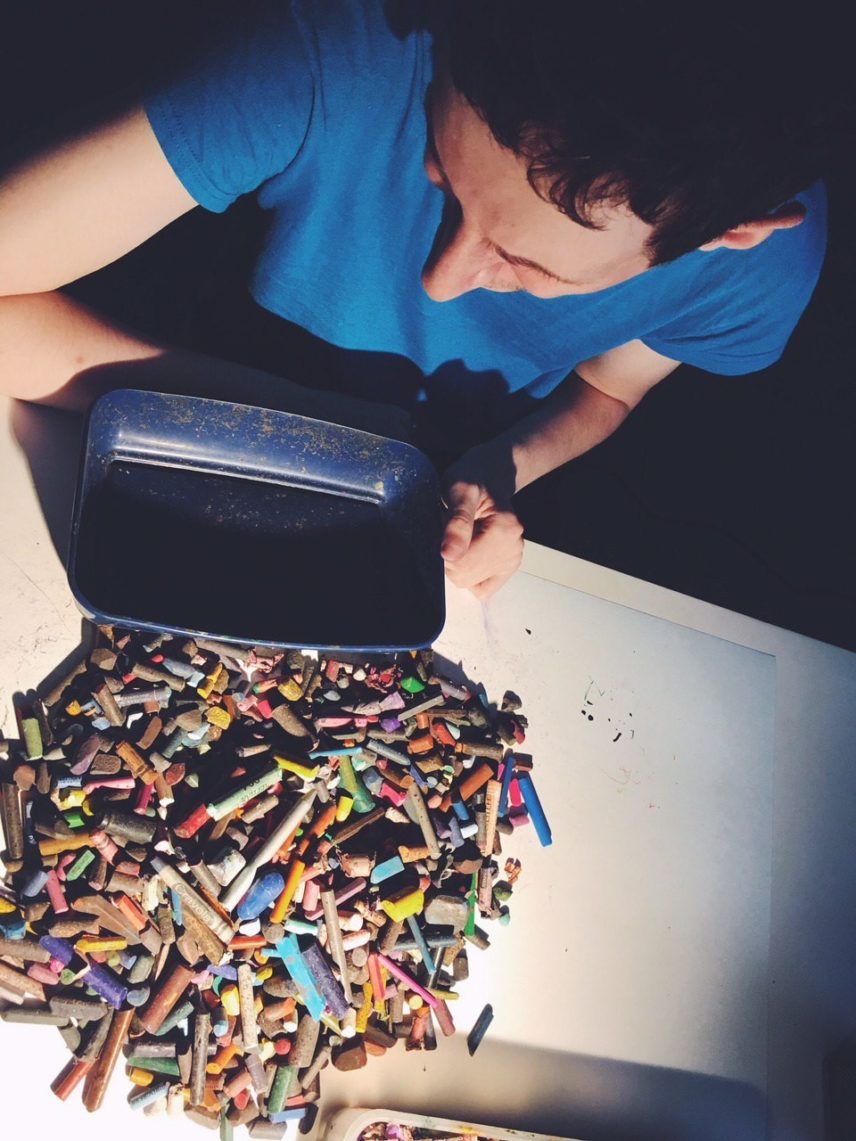 Photograph from above of a person with a pile of crayons and pastels