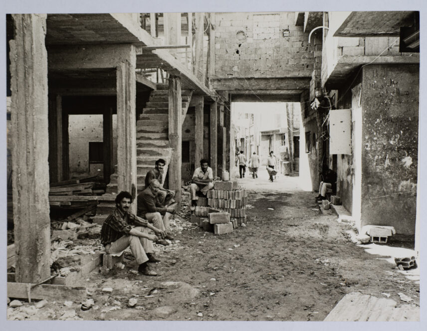 Photograph of four men sitting in an alley