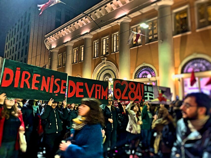 Photograph of women holding signs outdoors
