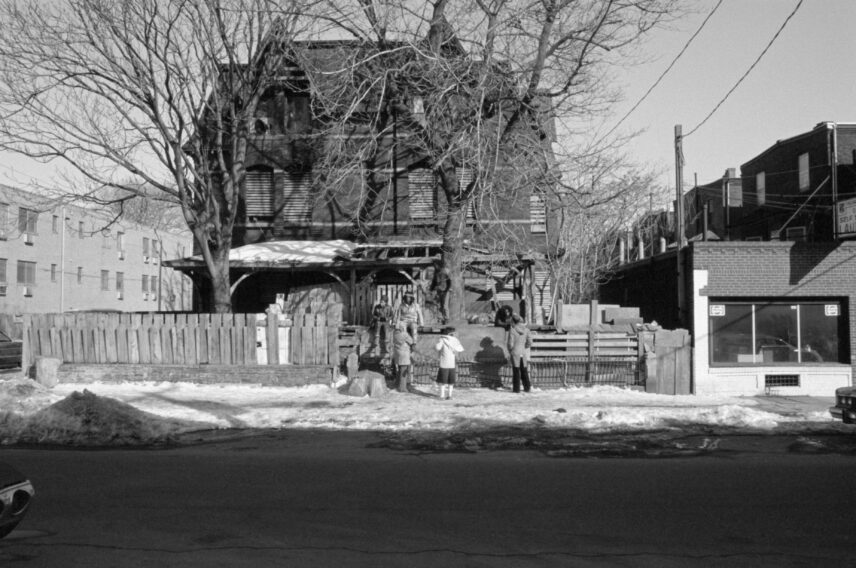 Photograph of a house with children and adults standing in front.
