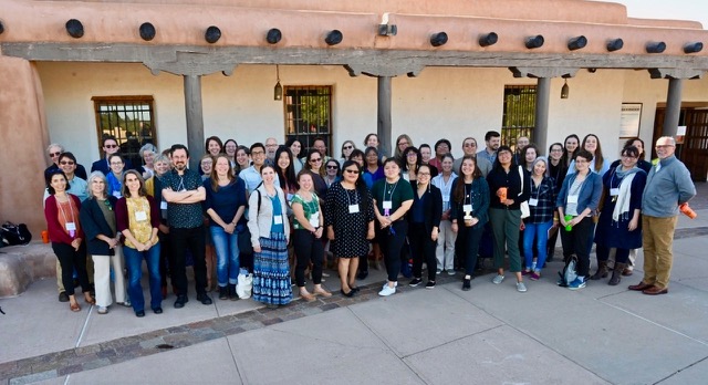 Group photograph of conference attendees, smiling and standing outside.