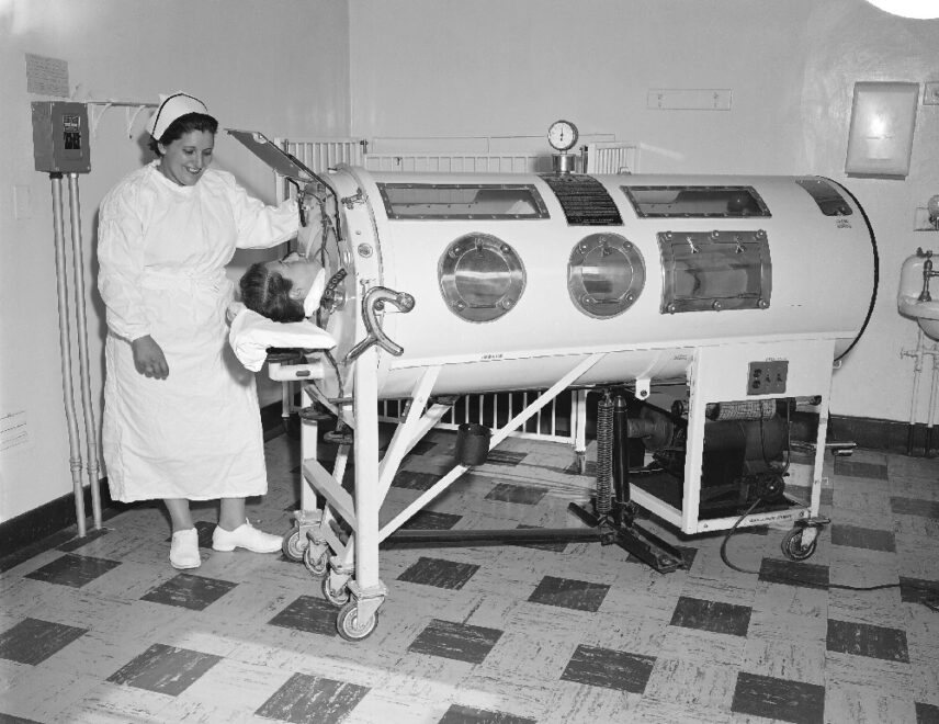 Black and white photograph of a nurse and a patient in an iron lung