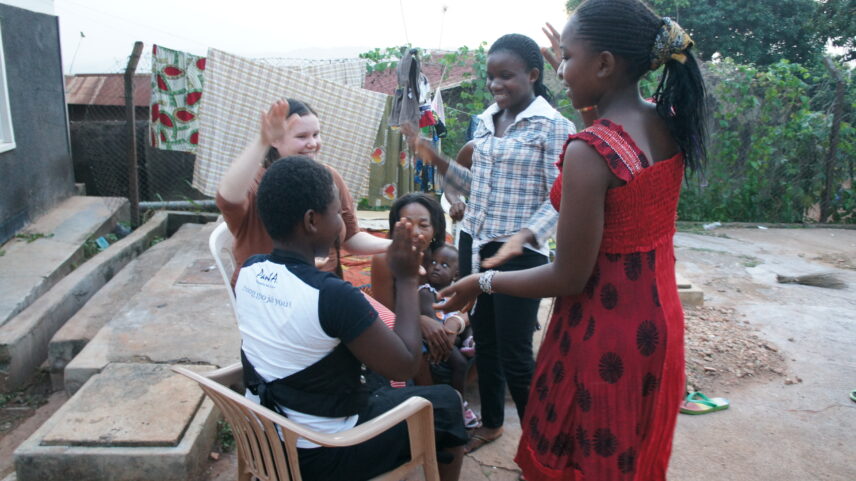 A picture of six smiling people in casual dress sitting and standing in a close circle in an outdoor courtyard space.