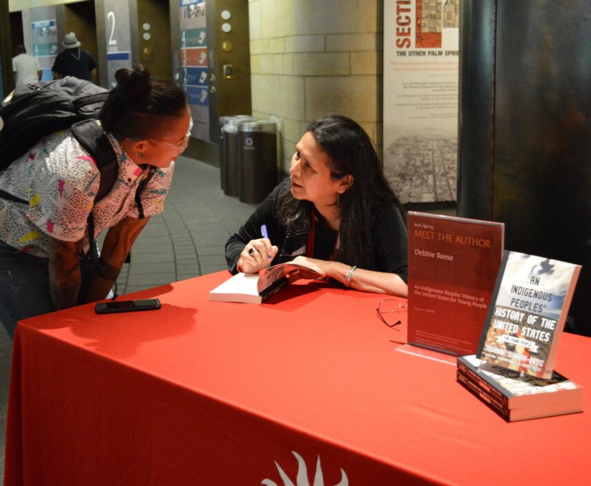 Photograph of two people talking over a table