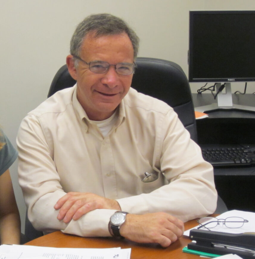 Photograph of a man indoors at a desk