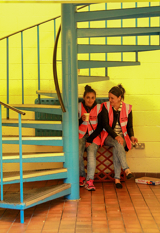 Photograph of two women sitting next to each other beside a staircase