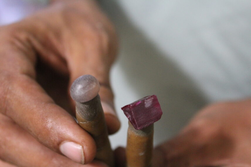 Photograph of hands holding two sticks with gems atop