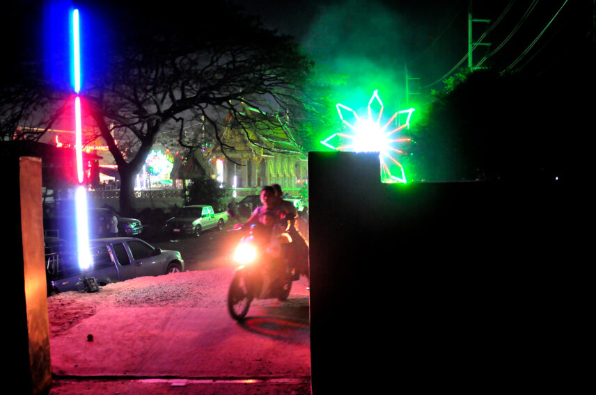 Photograph of a street at night, looking through an opening in a wall