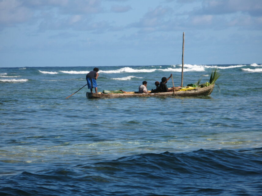 Photograph of people in a long canoe on the water