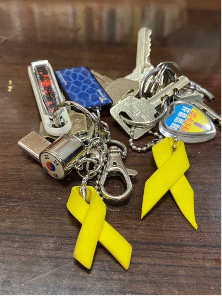 Two yellow ribbons, and a bundle of keys against a wooden table.