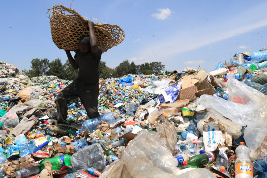 Photograph of a man outdoors walking through a large pile of trash