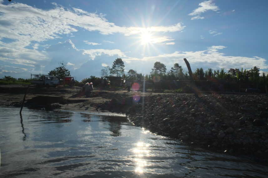 A picture of a riverbank on a sunny day taken from the water.