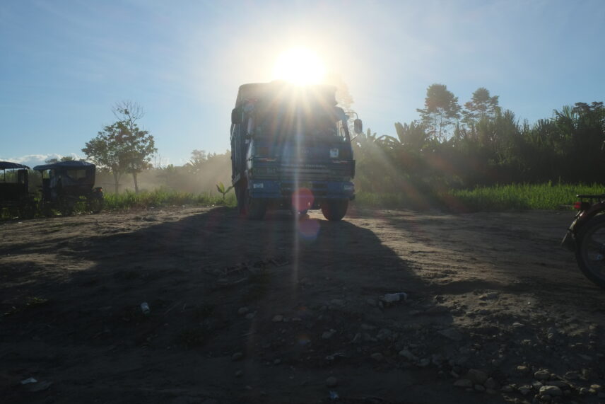 Photograph of a blue truck partially enveloped by sun rays.