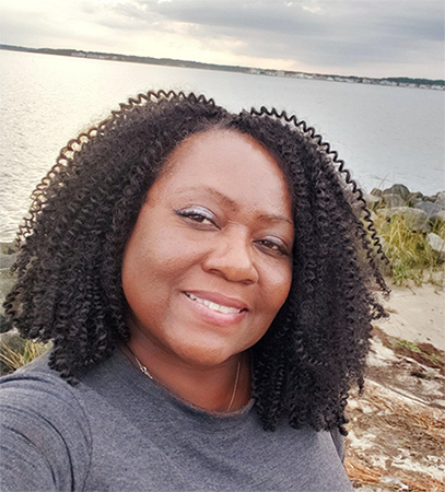 Photograph of a woman outdoors in front of a body of water