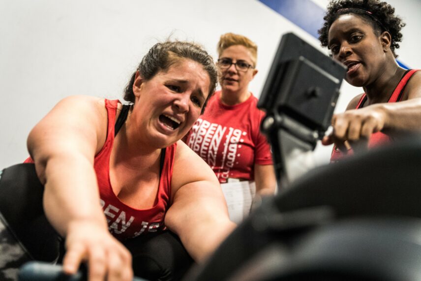 Photograph of a person mid-workout with two people standing nearby