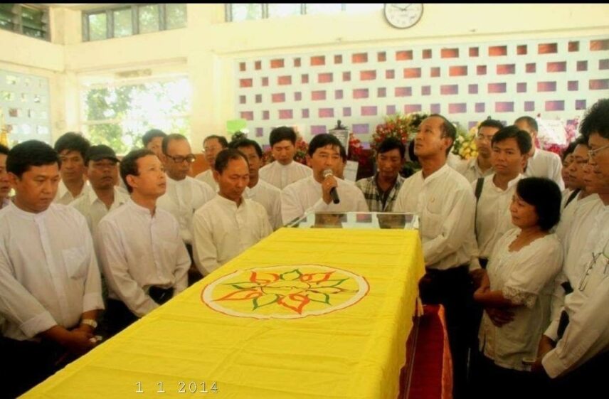 Photograph of people gathering indoors for a funeral