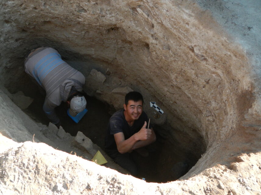 Photograph of two people in a deep hole