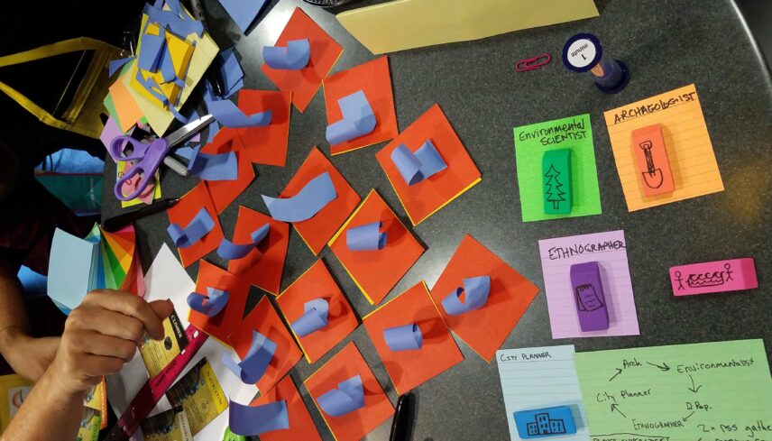 Photograph of a tabletop with paper, sharpies, and other stationery items