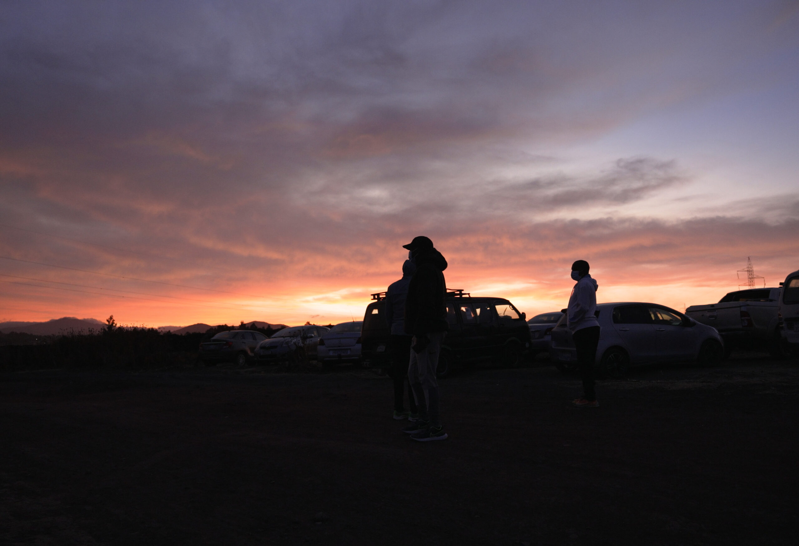 Photograph of a sunrise over parked cars