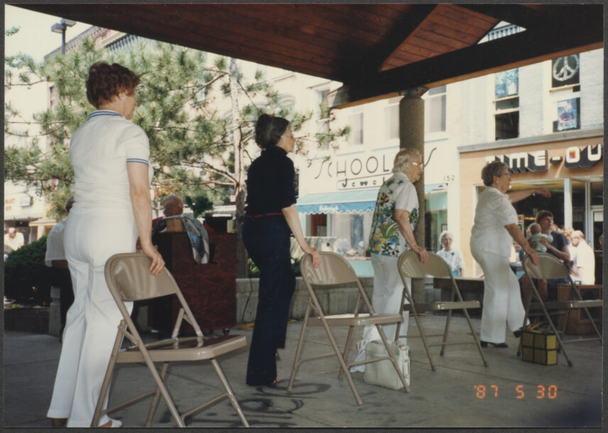 Photograph of four older women, standing behind chairs.